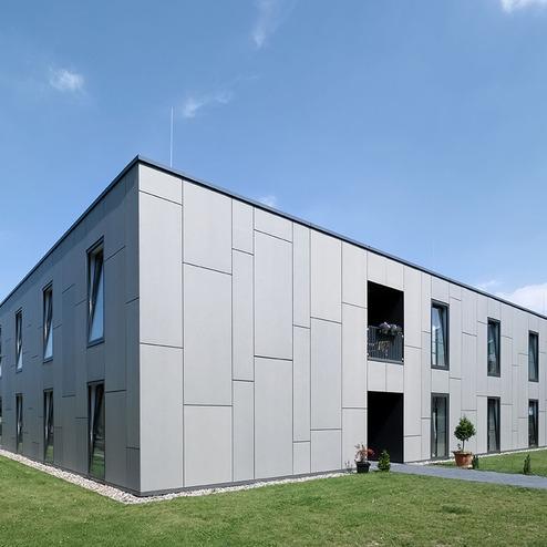 Graue Fassade mit Fenstern in der Seitenperspektive der Sozialimmobilie Demenzzentrum in Ratingen