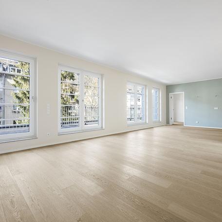 Wohnung von innen mit einem grossem Zimmer, einer Fensterfront und Balkon