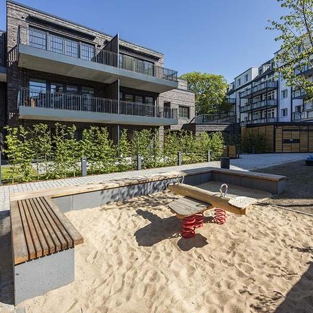 Wohnungen von außen mit Spielplatz und Sandkasten fuer Familien