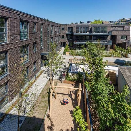 Wohnungen von aussen aus Vogelperspektive mit Schaukel und Sandkasten