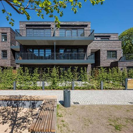 Wohnungen von aussen mit Sandkasten und Baenken