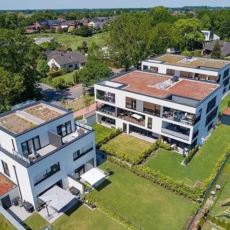 Drohnenperspektive der Wohnungen mit angelegten Gaerten, Terrassen, Dachterrassen und Gartenhuetten