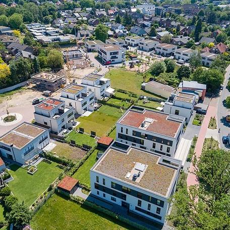 Drohnenansicht der Wohnungen mit Daechern, Gaerten, Zufahrten, Terrassen, Dachterrassen und Balkonen