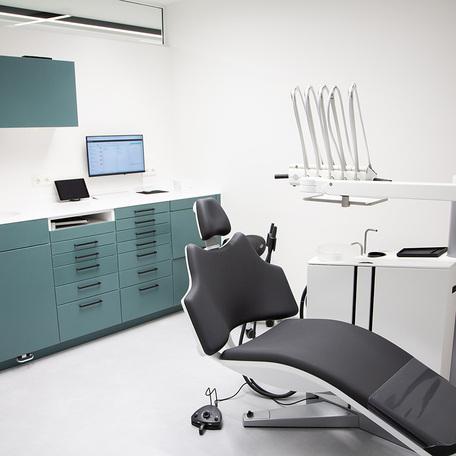 Patientenraum der Zahnarztpraxis des Gewerbegebaeude Kraemer in Wuppertal mit weissen Waenden, gruenen Moebeln und Zahnarztstuhl