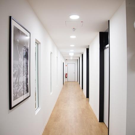 Flur der Zahnarztpraxis des Gewerbegebaeude Kraemer in Wuppertal mit weissen Waenden, Holzboden und Tueren