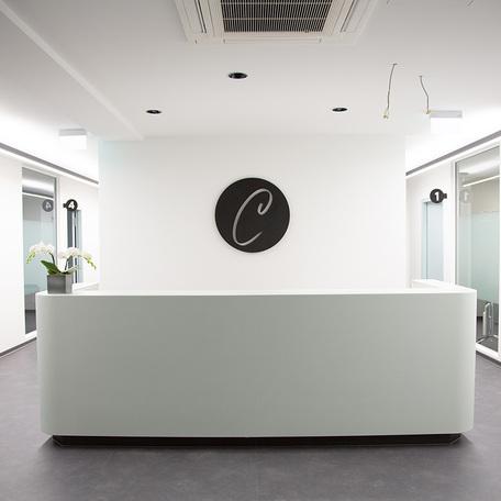 Weisse Tresen der Zahnarztpraxis des Gewerbegebaeude Kraemer in Wuppertal mit weissen Waenden und einem Logo