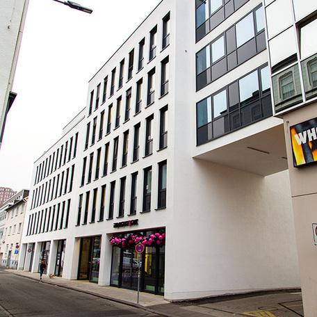 Gewerbegebaeude Kraemer in Wuppertal von aussen mit weisser Fassade, vielen Fenster und Einfahrt in den Hinterhof