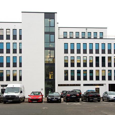 Gewerbegebaeude Kraemer in Wuppertal von aussen mit weisser Fassade, vielen Fenster und Parkplatz