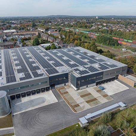 Drohnenperspektive auf die Auffahrt der Industrieimmobilie und Zufahrten fuer Lastkraftwagen mit den Toren geschlossen