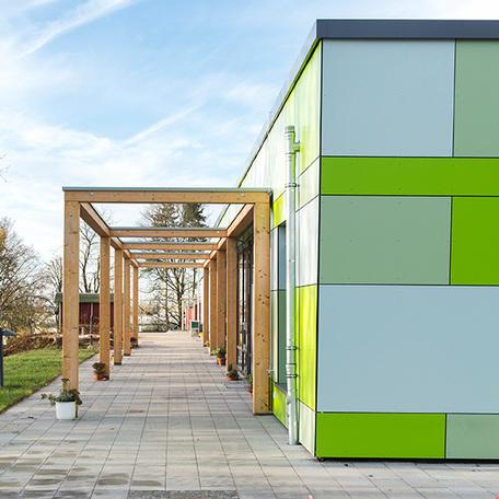 Seitenperspektive der gruenen Fassade mit der Ueberdachung der Kindertagesstaette in Wuppertal