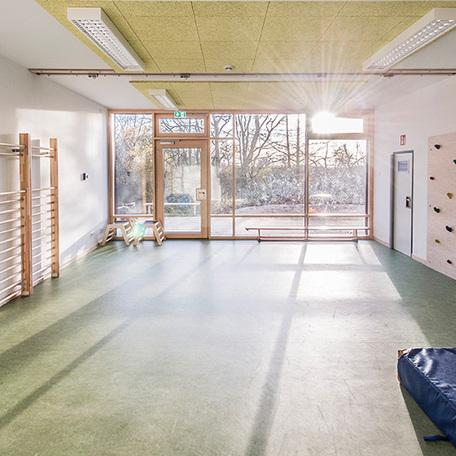 Raum zum Turnen mit Geraeten und Fensterfront welche in den Garten fuehrt der Kindertagesstaette in Wuppertal