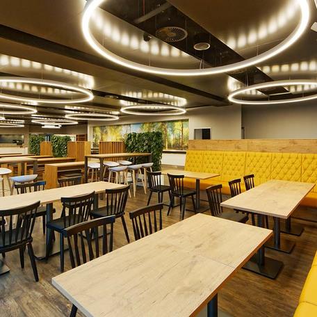 Warmer gemuetlicher Raum mit vielen Tischen und Sitzmoeglichkeiten des Erweiterungsbau eines Reiseveranstalters