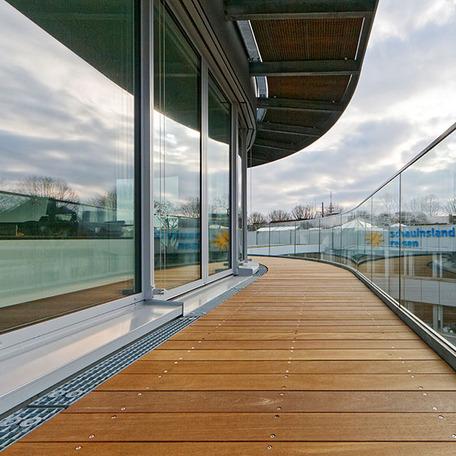 Balkon mit Holzboden und Glasgelaender des Erweiterungsbau eines Reiseveranstalters