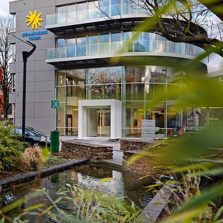 Gebaeude von aussen des Erweiterungsbau eines Reiseveranstalters mit grosser gebogenen Glasfassade und einem Logo