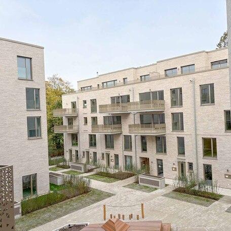 Aufnahme mit Fokus auf ein Wohnhaeus des Rohbaus in Duesseldorf mit aufwendiger hochwendiger Klinkerfassade, Dachbegruenung, Balkoenen, Terrassen, Eingaengen und Gehwegen