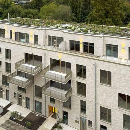 Drohnenaufnahme eines Wohnhaeuses des Rohbaus in Duesseldorf mit aufwendiger hochwendiger Klinkerfassade, Dachbegruenung, Balkoenen, Terrassen, Eingaengen und Gehwegen