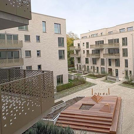 Aufnahme mit Fokus auf den Innenhof des Wohngebaeudekomplexes  des Rohbaus in Duesseldorf mit aufwendiger hochwendiger Klinkerfassade, Dachbegruenung, Balkoenen, Terrassen, Eingaengen, Spielplatz, Sitzmoeglichkeiten und Gehwegen