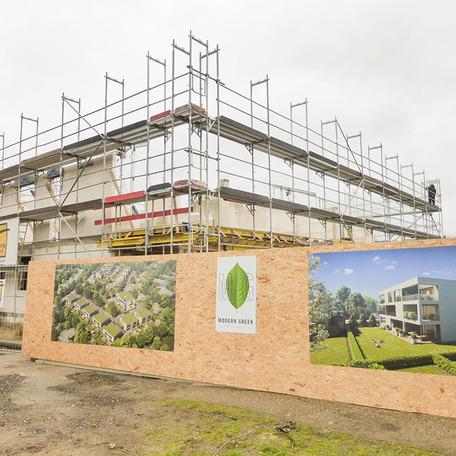Rohbau des Modern Green Bauprojekts am Efing in Bocholt mit Bauzaun und Visualisierungen der Wohngebaeude