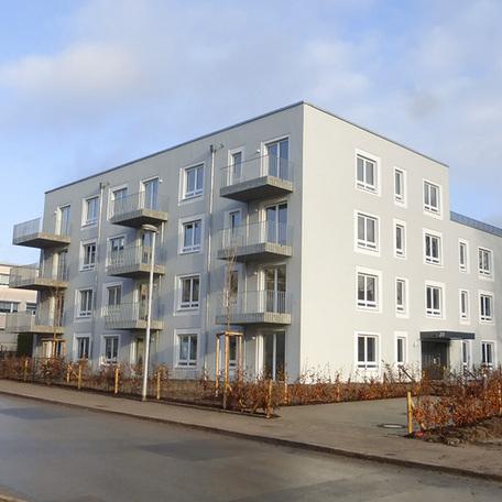 Wohnhaus in Bochum von aussen nach dem Rohbau bereit zur Abnahme mit grauer Fassade, Balkonen und einem Eingang