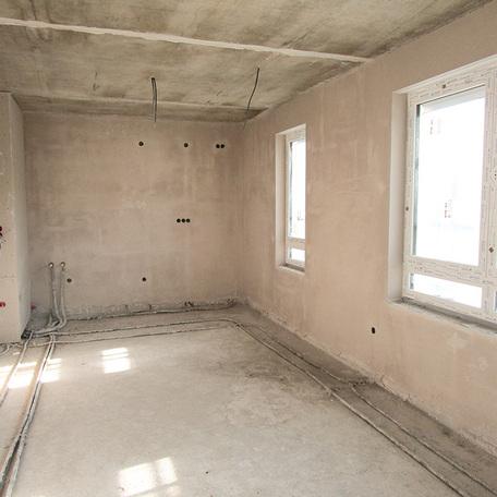 Zimmer eines Wohnhauses in Bochum mit eingebauten Fenster, gelegten Verkabelung und Rohren im Rohbauzustand