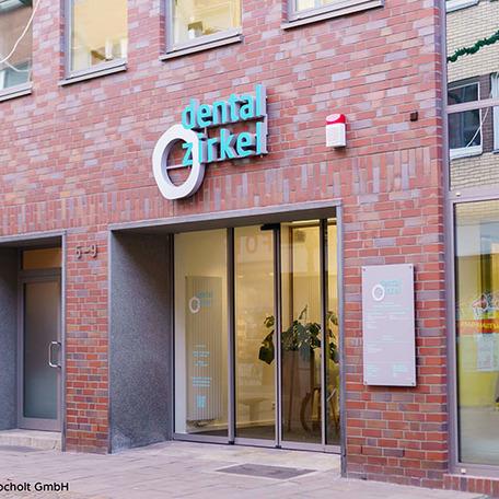 Sanierte Gewerbeflaeche in Bocholt von aussen mit Dentalzirkel Logo an roter Steinfassade