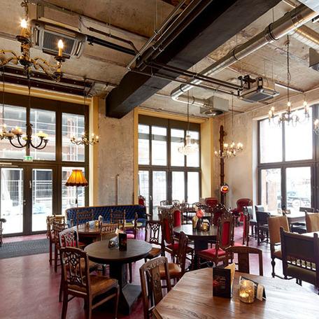 Restaurant des Gebaeude der umgebauten Schwanenhoefe in Duesseldorf mit Sitzmoeglichkeiten, Tischen, Dekoration, estetischen Deckenleuchten und grosser Fensterfronten