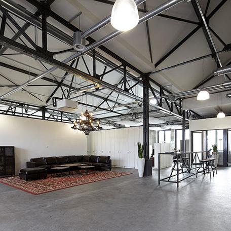 Halle innerhalb des Gebaeudes der umgebauten Schwanenhoefe in Duesseldorf mit grossem schwarzen Ledersofa, Tischen, Stehtischen, Hockern und weiterer Dekoration