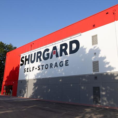 Selbstlagerhalle Shurgard in Neuss von aussen mit grossem Logo an der rot weissen grauen Fassade und einem Eingang