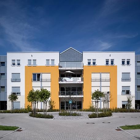 Frontalansicht des Eingangs des Seniorenpflegezentrum in Wuppertal von aussen mit weiss gelber Fassade und Kreisel