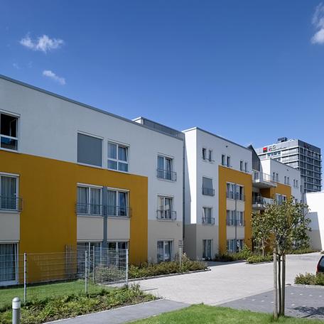 Wohnkomplex des Seniorenpflegezentrum in Wuppertal von aussen mit weiss beige gelber Fassade, Parkplaetzen und Gehwegen