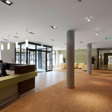 Empfang des Seniorenpflegezentrum in Alsdorf mit Empfangstresen, automatischen Schiebetueren aus Glas, Sessel als Sitzmoeglichkeiten und einem langen Flur