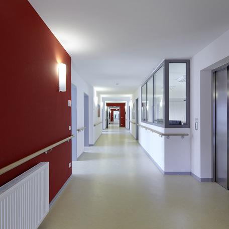 Flur des Seniorenpflegezentrum in Alsdorf, welcher zu den verschiedenen Zimmern fuehrt mit weiss-roten Waenden und Schwesternzimmer