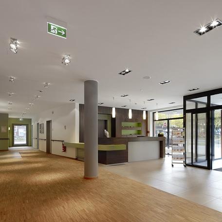 Empfang des Seniorenpflegezentrum in Alsdorf mit Empfangstresen, automatischen Schiebetueren aus Glas, Sessel als Sitzmoeglichkeiten und einem langen Flur