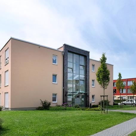 Seniorenzentrum in Duisburg von aussen mit beige Fassade und Blick durch Fensterfront auf das Treppenhaus
