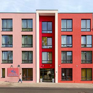 Frontalansicht des Seniorenpflegezentrum in Haan von aussen mit beige bis roetlichen Fassaden, grossen Fenstern, Eingang und Logo