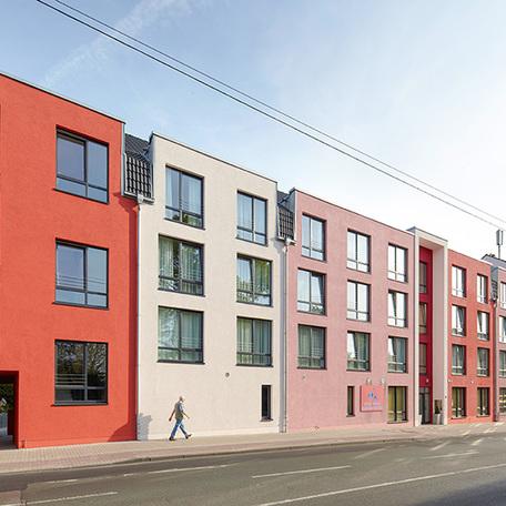 Seniorenpflegezentrum in Haan von aussen mit beige bis roetlichen Fassaden, grossen Fenstern, Strassenanbindung und Logo