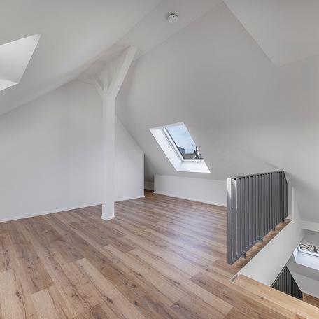 Mansarde einer Maisonette in Duesseldorf Lindenstrasse mit weissen Waenden, Treppe mit grauem Gelaender, Fenstern und weissem Pfosten