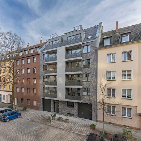 Drohnenaufnahme des Wohngebaeude in Duesseldorf Lindenstrasse von der Strasse aus mit grauer Fassade, Balkonen, Eingangstuer und Einfahrten