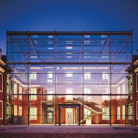 Beleuchteter Glashausanbau mit Treppe von innen und Schloss in Hintergrund in Oberhausen am Abend