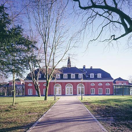 Schloss om Oberhausen mit roter Fassade und Park am Tag