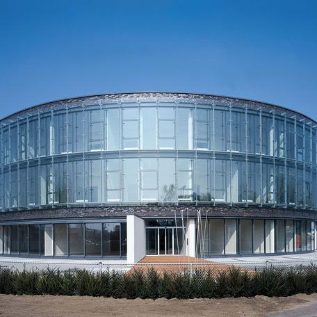 Verwaltungsgebaeude in Bocholt von aussen mit gewolbter beleuchteter Glasfront am Tag