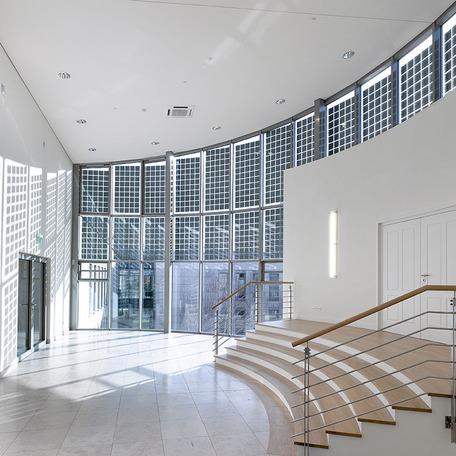 Verwaltungsgebaeude in Duisburg von innen mit grauen Fliesen, weissen Waenden, gewoelbter Fenster Fassade, Holztreppen und weissen Waenden