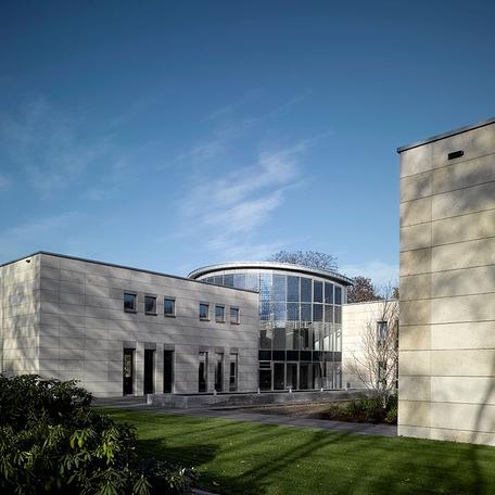 Eingang des Verwaltungsgebaeude in Duisburg von aussen mit gewoelbter Glasfront, beiger Fassade und Fussweg