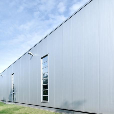 Seitenansicht des Verwaltungsgebaeude und Produktionshalle in Duisburg von aussen mit grauer Fassade und hohen Fenstern