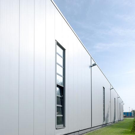 Seitenansicht des Verwaltungsgebaeude und Produktionshalle in Duisburg von aussen mit grauer Fassade und hohen Fenstern