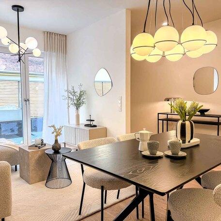 Wohnzimmer einer Musterwohnung des Bauprojektes Duesseldorf Oberbilk mit schwarzem Esstisch, Deko, Spiegeln, TV-Schrank und Couchtisch