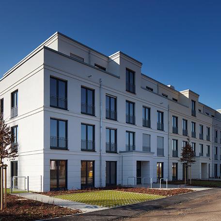Wohn- und Gewerbekomplex in Bonn von aussen mit beiger Fassade, Garten und Parkplaetzen fur Autos und Fahrraeder
