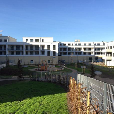 Wohn- und Gewerbekomplex in Bonn von aussen mit beiger Fassade, Garten, Balkonen, Spielplatz, Wiese und Gehwegen