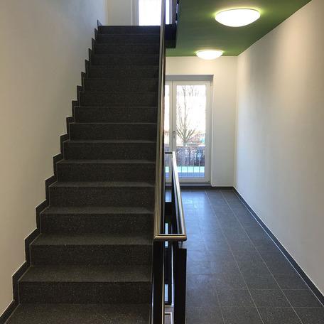 Flur des Wohn- und Gewerbekomplexes in Bonn von innen mit weissen Waenden, gruener Decke grauer Treppe und grauen Fliesen