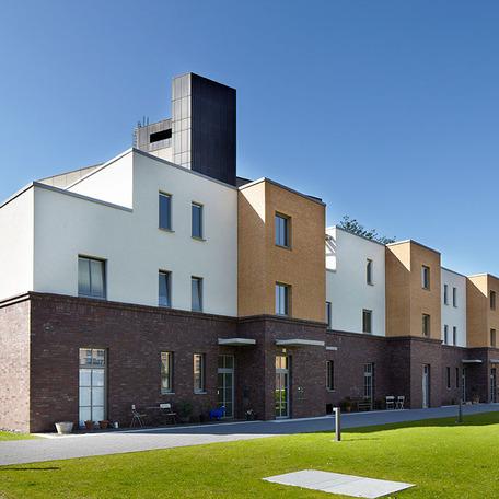 Wohn- und Gewerbekomplex in Duesseldorf von aussen mit Gehweg, brauner Klinker- und weisser Fassade, Gehweg und Wiese